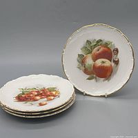 Stack of plates and one displayed showing apple motif and gold rim