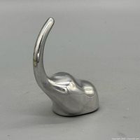 side view of polished aluminum figurine showing curved element and smooth body