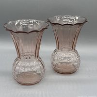 Front view of both pink glass vases showing quilted base and ribbed body