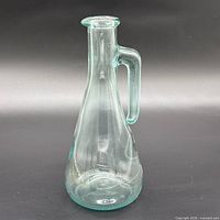 Front view of aqua glass carafe showing conical body and handle
