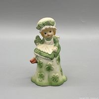 Front view of ceramic girl bell displaying clover motifs, colors and overall form