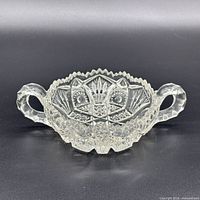 Front view of clear cut glass candy dish showing handles and pattern