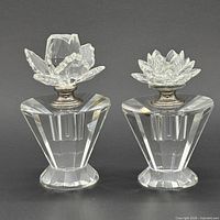 Front view of both cut crystal perfume bottles showing floral stoppers and silver-tone collars