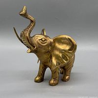 Left-front view of brass elephant with trunk raised