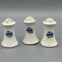 Front view of three white porcelain shakers with blue floral design