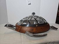 Full view of turtle-shaped serving tray showing wood base, metal cover, and metal head, flippers, tail.