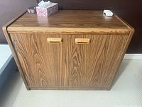 Front view of walnut veneer cabinet showing two recessed wooden handles and door fronts