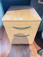 front view of light oak two-drawer cabinet on caster wheels