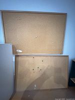 Two cork bulletin boards with wood frames, one leaning against wall, showing relative size and condition