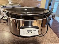 Front view showing stainless body, digital control panel, glass lid, power cord