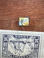 Front of 10-cent Dragonfly stamp on wood surface with partial view of glassine envelope