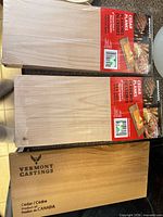 Two factory-wrapped cedar planks with Brinkmann label and separate Vermont Castings plank