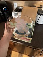 Hand holding clear glass bowl showing floral motif
