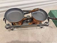 Overview of two pans on stand with burners beneath