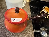 Orange-red enamel saucepan with lid and wood handle