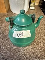 Front view of green aluminum kettle with lid and handle showing overall form