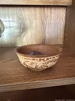 Wooden bowl with decorative carved exterior pattern and stone inside
