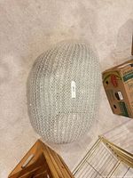 Top view of light gray knitted pouf on carpet