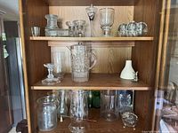 Cabinet view showing pitcher, vases, goblets, ceramic vase and assorted glass pieces