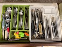 Overall view of two flatware drawer trays filled with mixed utensils and finger guards