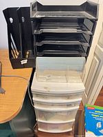 Stacked black letter trays, black magazine holders, clear desktop sorter on three-drawer unit