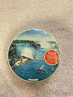 Top view of round tin showing Niagara Falls artwork and red Riley's label