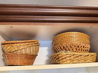 Six small baskets on shelf, four round nested, two rectangular stacked