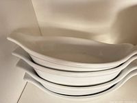 Stack of four white oval ceramic gratin dishes
