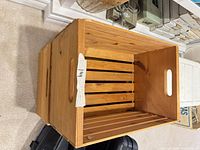 Side view of rectangular wooden crate showing slatted construction and cut-out handle