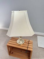 Full view of brass finish table lamp with cream square bell shade