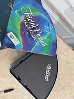 Wedge-shaped metal tin lid showing Trivial Pursuit Millennium branding