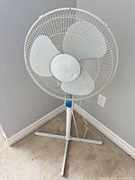 Front view of white pedestal fan showing blades, grill and cross base
