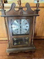 Full view of wooden wall clock with glass door and pendulum window