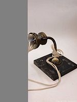 Side view showing brass arm, glass shade, cord, and marble base