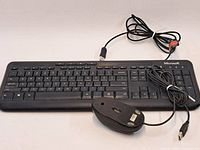Top view of Microsoft keyboard with USB cable coiled, Logitech mouse top and cable visible