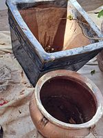 Square black glazed planter and round terracotta pot side by side