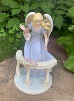 Front view of porcelain angel figurine behind curved railing