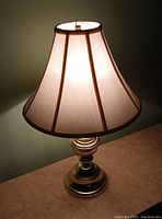 Full view of lit brass table lamp with shade