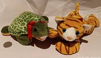 Turtle and tiger plush side by side with coin for scale