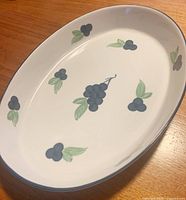 Top view of white oval dish with blueberry and leaf motif