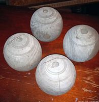 Four unfinished wooden spheres with center holes displayed top view