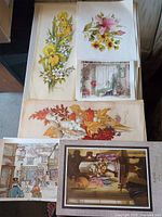 Assorted floral, interior, still life and street scene prints displayed