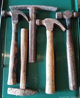 five assorted wood-handled hammers laid out