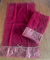 Both red cotton hand towels laid out showing brocade trim