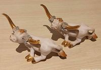 Front view of both porcelain cow figurines showing gilt horns, blue flowers