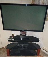 Full view of Panasonic TV on stand with Blu-ray player, VCR and remotes visible