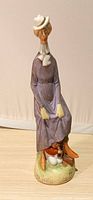 Front view of porcelain figurine showing woman, shoeshine boy, painted details