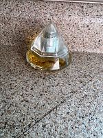 Full view of faceted glass perfume bottle filled with amber liquid, cap on