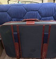 Front view of navy suitcase showing burgundy leather handle, trim and straps