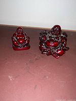 Front view of both red resin Laughing Buddha figurines